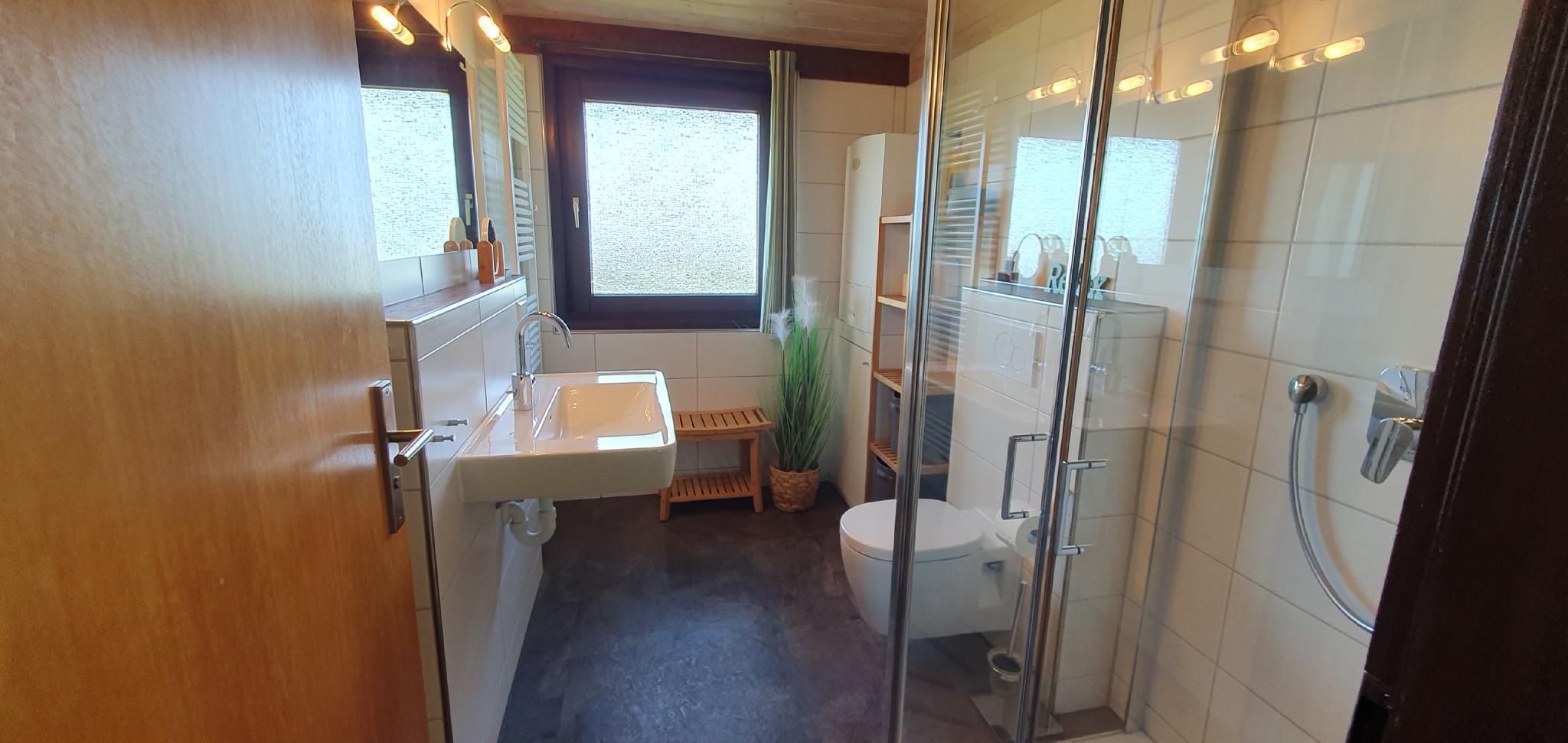 Bad mit Waschtisch (links), rechts in der Mitte Toilette und rechts vorne die Dusche